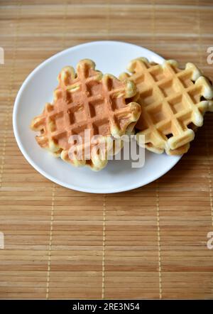 Goldene köstliche wiener Waffeln aus Holz. Holzhintergrund. Himbeere isoliert. Gourmetessen. Stockfoto