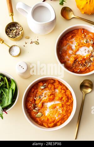 Gesundes Mittagessen, köstliche Kürbiscremesuppe mit Sonnenblumen und Kürbiskernen, Sesam und Flachs und mit Kokosmilch, gemischter Salat, Draufsicht Stockfoto
