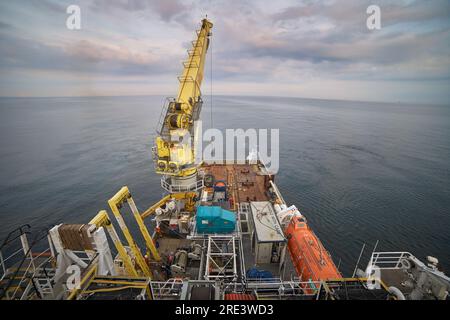 Blick auf das Hauptdeck des Offshore-Schiffes mit Kran und Containern. Dynamische Positionierung des Schiffes in Betrieb. Offshore-Kran. Taucher unterstützen das Hauptdeck des Schiffs. Stockfoto