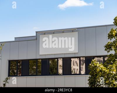 Leerer Firmenname auf einem Industriegebäude. Vorlage für ein Logo auf einer Fassade. Außenansicht der Produktionshalle mit leerem Platz für eine Anzeige. Stockfoto