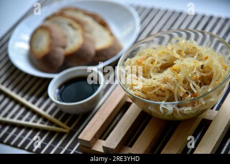 Koreanische Reisnudeln mit Fleisch und Gewürzen. Nudeln mit Soße und Brot. Nudelstöcke. Stockfoto