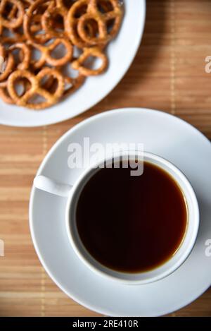 Eine Teekanne mit Tee und eine Tasse mit Untertasse und Brezeln sind salzig. Stockfoto