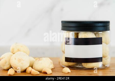 Macadamianüsse und Kekse in einer Plastikbox auf einem Holztisch Stockfoto