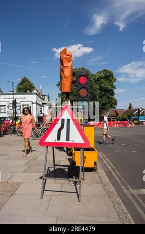 Temporäre Ampeln und ein Road Narrows Straßenschild links Highway Code auf einer Straße im Südwesten von London, England, Großbritannien Stockfoto