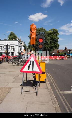 Temporäre Ampeln und ein Road Narrows Straßenschild links Highway Code auf einer Straße im Südwesten von London, England, Großbritannien Stockfoto