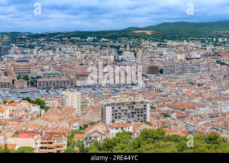 Stadtbild über Marseille, aufgenommen von der Basilika Notre-Dame von La Garde, mit Blick auf Terrakotta-Dächer, verwinkelte Straßen und entfernte Berge. Stockfoto