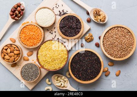 Verschiedene Superfoods in der kleinen Schüssel auf farbigem Hintergrund. Superfood wie Reis, Chia, Quinoa, Linsen, Nüsse, Sesamsamen, Mandeln. Draufsicht. Stockfoto