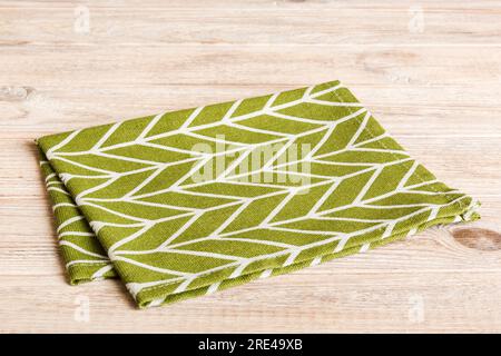 Draufsicht mit grüner Serviette auf Tischhintergrund isoliert. Gefaltetes Tuch für Modell mit Kopierbereich, flach liegend. Minimalistischer Style. Stockfoto