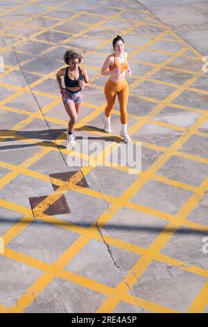 Blick von oben auf zwei Freunde, die entlang der Stadtstraße laufen Stockfoto