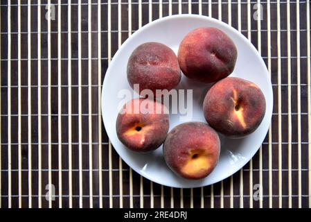 Saftige rote und gelbe Pfirsiche auf einem weißen Teller. Köstliche Pfirsiche zum Mittagessen. Gesunde Ernährung. Vegetarisches Essen. Stockfoto