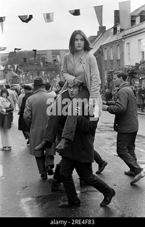 Ein Paar, das Spaß hat, ein Mädchen, das auf den Schultern eines Freundes reitet. Helston Furry Dance Cornwall 1970er Helston, Cornwall, UK 1970 HOMER SYKES Stockfoto