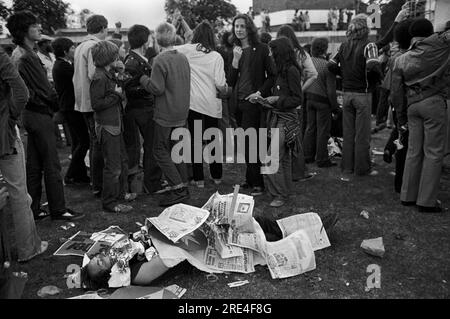 Erschöpfter Demonstrant, verpasst das Konzert, er schläft schnell. Er wurde von alten Zeitungen im Brockwell Park bei einem Rock Against Rassismus Konzert vertuscht. Sie marschierten 1978 vom Hyde Park London nach Brockwell Park nahe Brixton South London. HOMER SYKES AUS DEN 1970ER JAHREN. Stockfoto