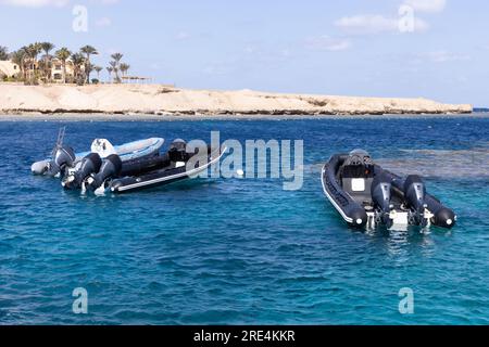 Drei aufblasbare Boote stehen leer vor Anker an einem Korallenriff mit kristallklarem Wasser. Stockfoto