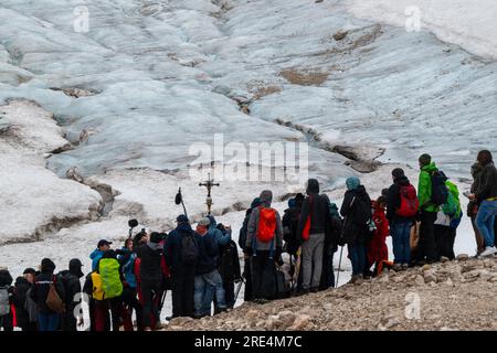 Garmisch Partenkirchen, Deutschland. 25. Juli 2023. Der katholische Priester Florian Hammerl und der protestantische Priester Uli Wilhelm (beide versteckt) halten vor den Überresten des Gletschers (im Hintergrund), eine Prozession für den Zugspitz-Gletscher. Zusätzlich zu Informationen und Gebeten wird der Gletscher gesegnet und ein für den Anlass zusammengestelltes Bergquiem wird mit drei Sängerinnen und einem Windchor Premiere erhalten. Kredit: Peter Kneffel/dpa/Alamy Live News Stockfoto