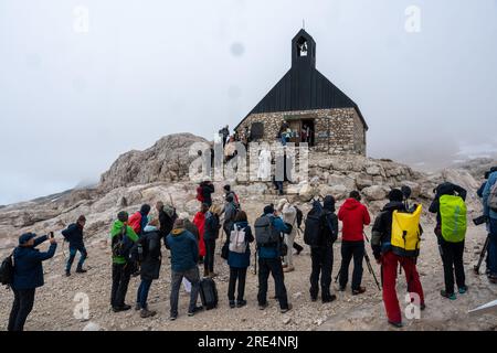 Garmisch Partenkirchen, Deutschland. 25. Juli 2023. Der katholische Priester Florian Hammerl (l) und der protestantische Priester Uli Wilhelm (r) führen vor der Mariä Heimsuchung-Kapelle eine Prozession für den Zugspitze-Gletscher. Zusätzlich zu Informationen und Gebeten wird der Gletscher gesegnet und ein für den Anlass zusammengestelltes Bergquiem wird mit drei Sängerinnen und einem Windchor Premiere erhalten. Kredit: Peter Kneffel/dpa/Alamy Live News Stockfoto