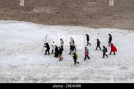 Garmisch Partenkirchen, Deutschland. 25. Juli 2023. Der katholische Priester Florian Hammerl (2. von links) und der protestantische Priester Uli Wilhelm (3. von links) führen eine Prozession für den Zugspitze-Gletscher. Zusätzlich zu Informationen und Gebeten wird der Gletscher gesegnet und ein für den Anlass zusammengestelltes Bergquiem wird mit drei Sängerinnen und einem Windchor Premiere erhalten. Kredit: Peter Kneffel/dpa/Alamy Live News Stockfoto