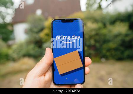 Hamburg, Deutschland - 12. Juni 2023: POV männliche Hand hält das neue iphone 15 pro in der Hand mit Amazon Prime Day Shopping Website Promo auf dem Flüssigretina Display - Gartenhintergrund Stockfoto