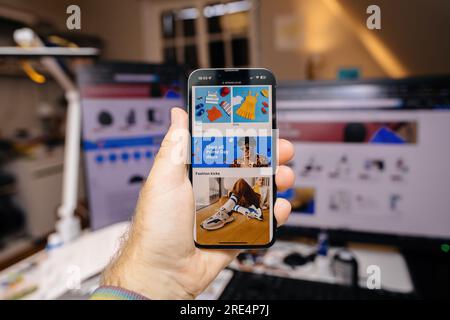 Hamburg, Deutschland - 12. Juni 2023: POV männliche Hand hält das neue iphone 15 pro in der Hand mit Amazon Prime Day Shopping Website Promo auf dem Liquid Retina Display - Kreativraum im Hintergrund Stockfoto