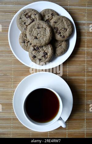 Teepaar und Haferflocken-Kekse mit Schokolade auf einer Matte. Köstliches Frühstück mit Tee und süßen Plätzchen. Gesundes Getränk. Stockfoto