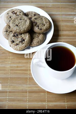 Teepaar und Haferflocken-Kekse mit Schokolade auf einer Matte. Köstliches Frühstück mit Tee und süßen Plätzchen. Gesundes Getränk. Stockfoto