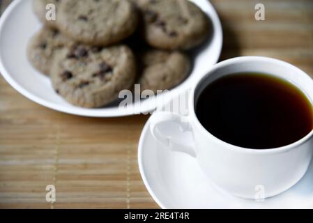 Teepaar und Haferflocken-Kekse mit Schokolade auf einer Matte. Köstliches Frühstück mit Tee und süßen Plätzchen. Gesundes Getränk. Stockfoto