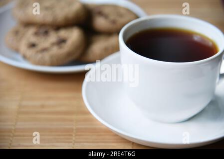 Teepaar und Haferflocken-Kekse mit Schokolade auf einer Matte. Köstliches Frühstück mit Tee und süßen Plätzchen. Gesundes Getränk. Stockfoto