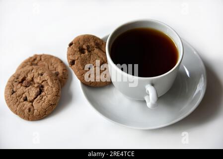 Teepaar und Haferflocken-Kekse mit Schokolade auf weißem Hintergrund. Köstliches Mittagessen mit Tee und süßen Plätzchen. Porzellantee-Set mit einem heißen Getränk. Gute Güte Stockfoto