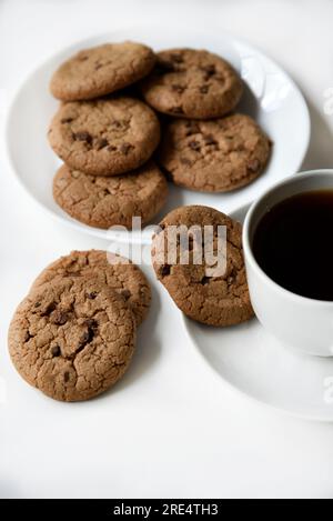 Teepaar und Haferflocken-Kekse mit Schokolade auf weißem Hintergrund. Köstliches Mittagessen mit Tee und süßen Plätzchen. Porzellantee-Set mit einem heißen Getränk. Gute Güte Stockfoto