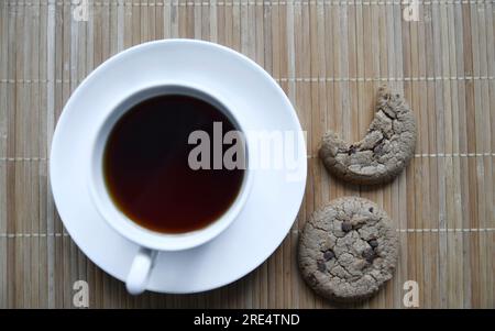 Teepaar und Haferflocken-Kekse mit Schokolade auf einer Matte. Köstliches Frühstück mit Tee und süßen Plätzchen. Gesundes Getränk. Stockfoto