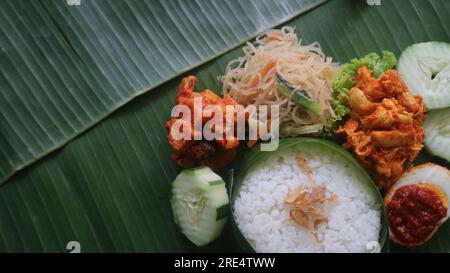 Schmackhafter Reis, Nudeln, Gurken und gewürzte Kartoffeln auf Bananenblatt. Traditionelles indonesisches Essen Stockfoto