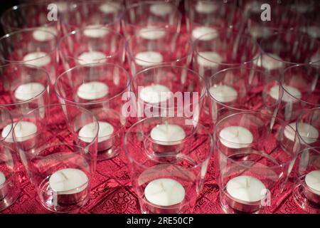 Kerzen in Gläsern. Viele Kerzen auf dem Tisch. Struktur transparenter Becher. Wachskerzen. Stockfoto