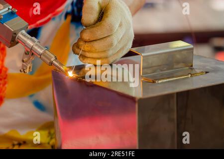 Nahaufnahme: Schweißer Hände mit Handlaserschweißmaschine Stockfoto