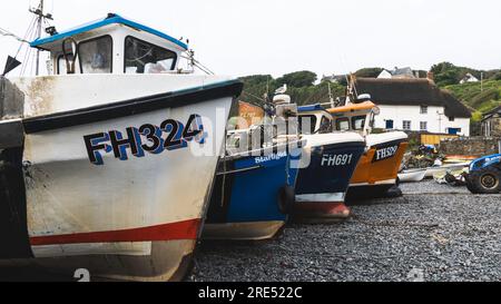 CADGWITH, CORNWALL, GROSSBRITANNIEN - 1. JULI 2023. Traditionelle kornische Fischerboote aus dem Wasser und am Kieselstrand am beliebten Touristenziel Stockfoto