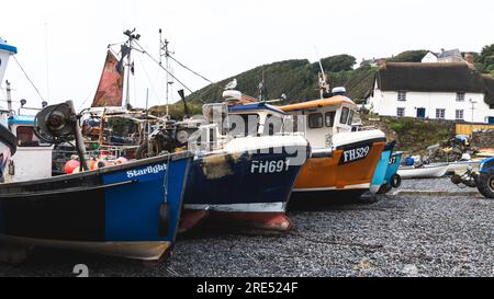 CADGWITH, CORNWALL, GROSSBRITANNIEN - 1. JULI 2023. Traditionelle kornische Fischerboote aus dem Wasser und am Kieselstrand am beliebten Touristenziel Stockfoto