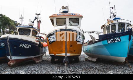 CADGWITH, CORNWALL, GROSSBRITANNIEN - 1. JULI 2023. Traditionelle kornische Fischerboote aus dem Wasser und am Kieselstrand am beliebten Touristenziel Stockfoto