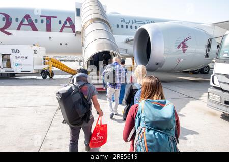 Passagiere mit Gepäck, die das Flugzeug der Qatar Airline betreten Stockfoto