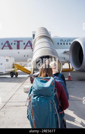 Passagiere mit Gepäck, die das Flugzeug der Qatar Airline am Flughafen Doha betreten Stockfoto