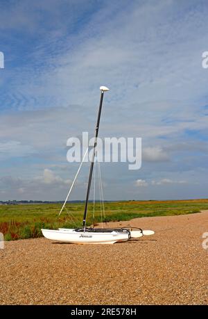 Ein Katamaran Hobie Cat 15 strandete über dem Hochwasserrand am Kiesstrand an der Nordnorfolkküste bei Cley Next the Sea, Norfolk, England, Großbritannien. Stockfoto