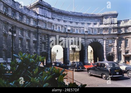 Verkehr entlang des Admiralty Arch mit Blick auf die Mall zum Buckingham Palace, London, England, Großbritannien. Etwa 1980er Jahre Stockfoto