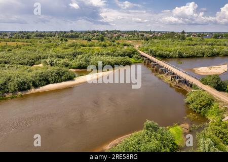 Draufsicht von der Drohne über den Fluss Sluch, die alte Brücke und das Dorf Liukhcha in Rivne, Ukraine. Stockfoto