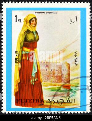 FUJEIRA - CIRCA 1972: Ein in Fujeira gedruckter Stempel zeigt das orientalische Frauenkleid, ca. 1972 Stockfoto