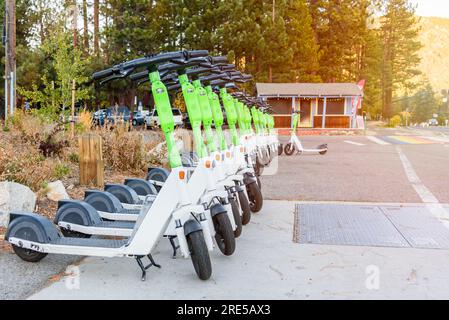 Eine Reihe elektrischer Roller, die sich im Herbst bei Sonnenuntergang auf einer Straße in einem Bergresort teilen können Stockfoto