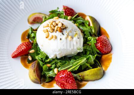 Burrata-Käse, italienischer Salat, Erdbeeren, Rucola, Feigen, Pinienkerne, Balsamico Stockfoto