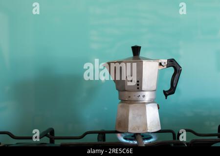 Moka-Kaffee auf Gasflamme. Typisch italienisches Kaffeewerkzeug. Espresso-Kaffee mit hellblauem Hintergrund und Kopierbereich Stockfoto