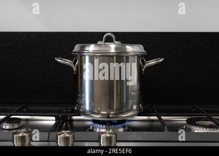 Decken Sie einen Topf, mit dem Sie kochen, mit einem Deckel ab. Der Stahltopf ist zum Kochen auf einem Gasherd überdacht. Konzept für bewährte Verfahren zur notwendigen Energieeinsparung Stockfoto