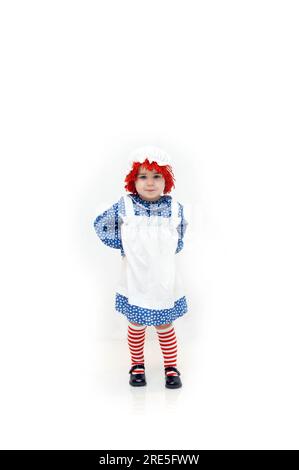 Das altmodische Raggedy-Ann-Kostüm wird von einem süßen kleinen Mädchen mit einem süßen kleinen Grinsen getragen. Mit Schürze und gestreiften Socken ist ihr Haar wieder frisch Stockfoto
