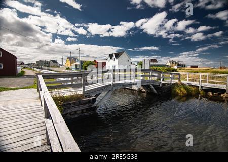 Holzsteg und Brücke über einen Kanal mit entfernten Strandhäusern an der Ostküste auf Bonavista Neufundland Kanada. Stockfoto