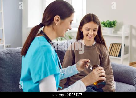 Lächelnde Kinderärztin gießt etwas Hustensaft in den Löffel für ein glückliches Kind Stockfoto