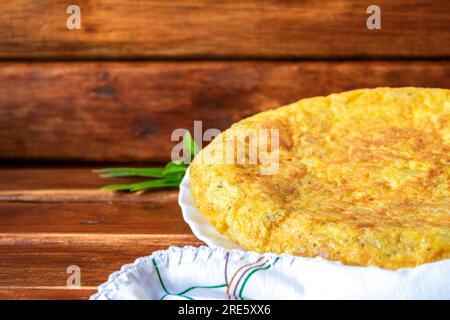 spanisches Kartoffelomelett mit Knoblauch und Petersilie. Nahaufnahme von Kartoffelomelette auf braunem Holzhintergrund Stockfoto