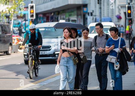 Gruppe von möglicherweise japanischen Touristen, die im Sommer auf einer geschäftigen Straße in Brighton & Hove, East Sussex, England, spazieren. Stockfoto